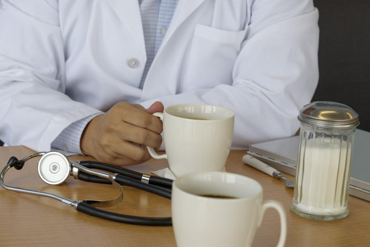 A doctor sharing coffee and a chat with a colleague on a break at their office. 